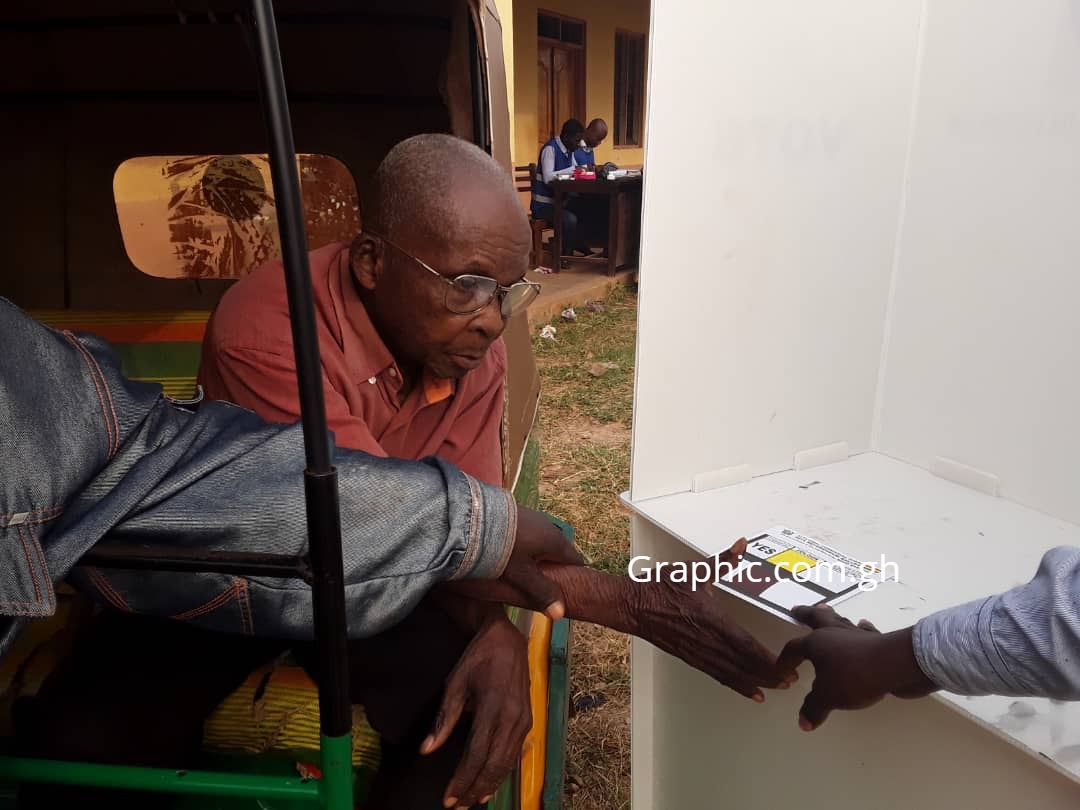 84-year-old Samuel Kwaku Yeboah being assisted to cast his vote