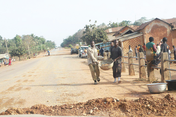 Some residents of Aburaso carrying sand in pans to fill potholes as well as construct speed humps on the road to help reduce overspeeding on that stretch.