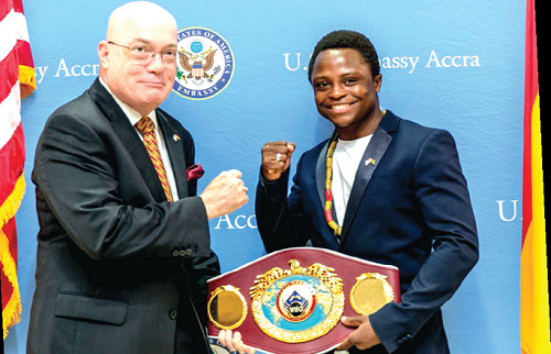 Isaac Dogboe (left) presents his belt to Ambassador Robert Jackson during the visit to the US Enbassy