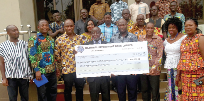 Mr Yaw Kyei (4th right) and Prof. Tuah (4th left) being assisted by officials of the GNPC and UENR to display the cheque after it had been presented