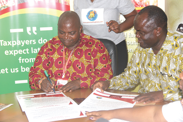  Ransford Tetteh (left), Ag. Managing Director, Graphic Communications Group Limited (GCGL), signing the punctuality pledge during the ceremony. Looking on is Mr Emmanuel Amarquaye (right), Founder, Punctuality Ghana. Picture: EDNA ADU-SERWAA