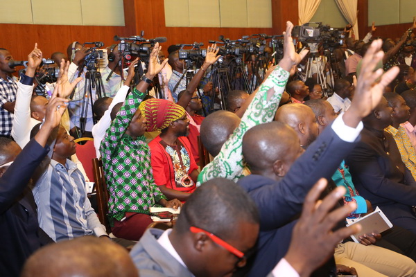  Some journalists trying to catch the eye of the moderator to ask questions