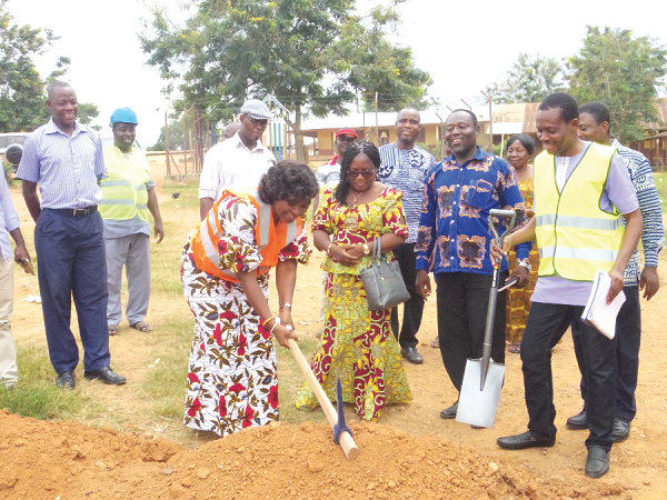  Mrs Justina Marigold Assan cutting the sod for the construction of the classroom block. Looking on is Mrs Elizabeth Helen Essel, and other officials of the assembly. INSET: The old classroom block