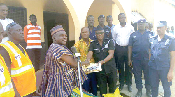 Mr Jerry Asamane Regional Director of NADMO, (in smock) presenting the relief items to the Bolgatanga Municipal Commander (in uniform) while Chief Inspector Amewugah (middle) and others look on