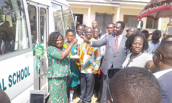 The Deputy Minister (in suit) presenting the keys to the bus to the District Director of Education, Madam Augustina Konadu Yiadom (left), at Kuntanase while the DCE of Bosomtwe, Mr Joseph Kwasi Asuming and other dignitaries look on