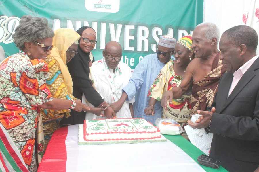 Prof. Delle (middle) being assisted by members of the party to cut the 69th anniversary cake