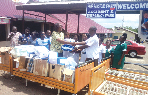 Dr Derek Bonsu (right) receiving the items from Ms Georgina Graham (left), the Mfantseman Municipal Director of  Health Services while staff of the hospital look on