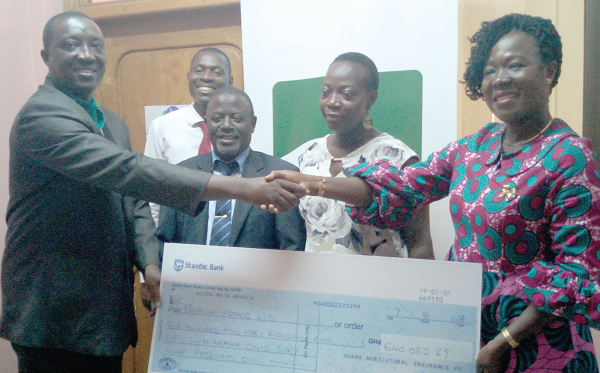 Madam Gladys Simpson (right) receiving the cheque from Mr Jerry Quartson, while Alhaji  Ali Katu (2nd left) and other staff of the insurance company look on