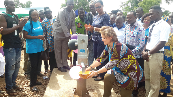 Ms Anne-Claire Dufay fetching water from a borehole after inaugurating the WASH facility 