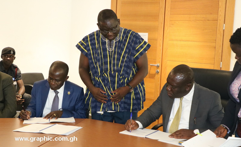 Vice Chancellor of the KNUST, Prof. Kwasi Obiri-Danso, left, and Deputy Communications Minister, Vincent Sowah Odotei, append their signatures to the agreement while Mr Victor Adadjie, the project's Monitoring and Evaluation Coordinator looks on.