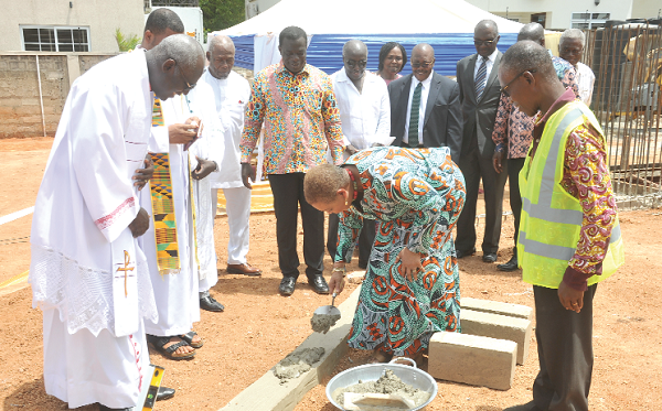 Ms Joyce Aryee laying the foundation stone at the site. Looking on are Mr Ignatius Baffour Awuah (in Africa print) and some invited guest. Picture: EBOW HANSON