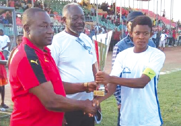 Ampem Darkoa captain, Justice Tweneboah, receives the Super Cup trophy from Augustine Asante, the Brong Ahafo RFA chairman, while Nii J.B Torto I, WLB member, looks on.