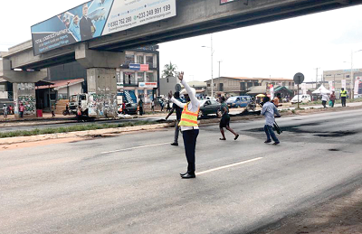 A policeman directing traffic under one of the footbridges to help pedestrians cross the highway at Adentan. Picture: Maxwell Ocloo