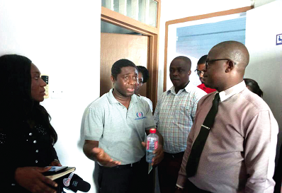Mr Allotey Addo (left), being questioned by personnel of the police CID, at his clinic