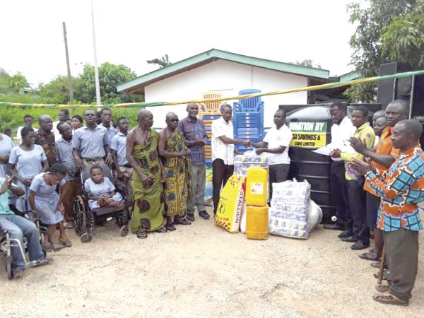 Mr Felix Ahiadome, presenting the items to Mr Fatau Fuseini , while some students, teachers  and some elders of the Jachie-Pramso community look on