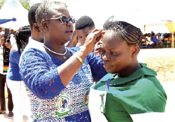  Mrs Blankson puts on a cap for a newly matriculated student nurse at the ceremony. 