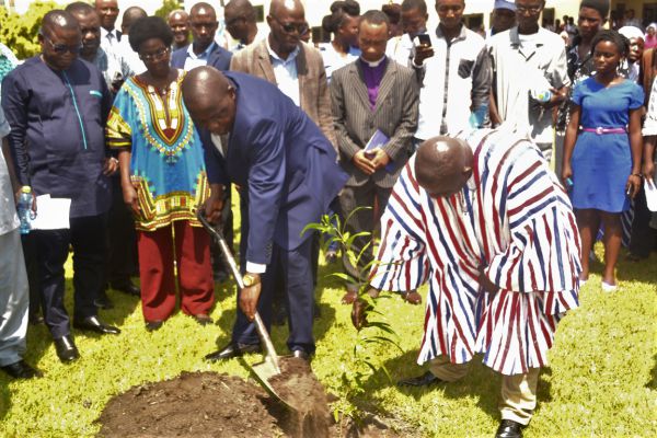 •  Rev. Fr Prof. Anthony Afful-Broni (with shovel}, being assisted by Mr Paul Osei Barimah, registrar (in smock) to plant the anniversary tree while other officials and students look on 