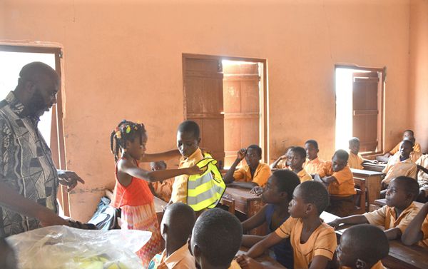  Empress Esi Amoah (arrowed) putting a reflector on a pupil during one of her road safety campaigns.