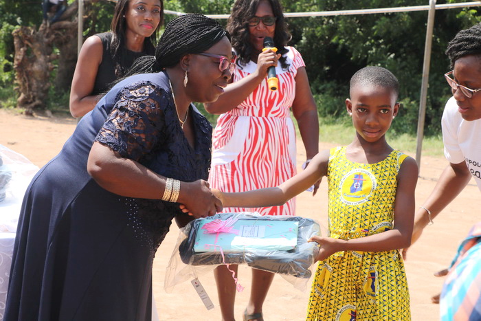 Madam Rosina Adorbor, the Kpone Katamanso Municipal Education Director handing over a prize Miss Janet Quartey for being the best pupil in Primary 2.
