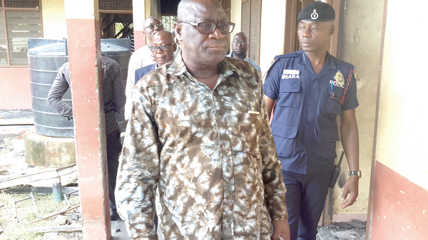  Mr Suleman Alhassan, (in sunglasses) being conducted round the school. (INSET) The remains of the school block