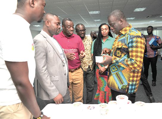 Mr Ignatius Baffour-Awuah, examining packaged shea butter after the launch. With him are Dr Ibrahim Mohammed Awal (3rd left)  and some invited guest