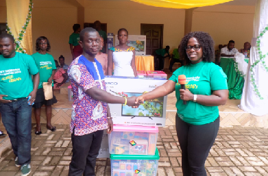 Mrs Mercy Quansah Ansah presenting two flat screen TV sets, two pen drives, textbooks and other educational materials to Mr Patrick Amoh Ennin, the Headmaster of Hweakwae Roman Catholic Primary School, for the school’s outstanding performance in reading library books