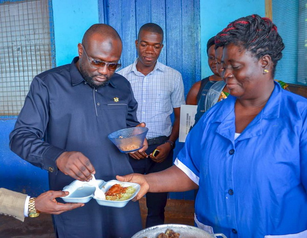 Alhaji Abduil-Wahab tasting food prepared for students at the Armed Forces Senior High/Technical School during his visit.