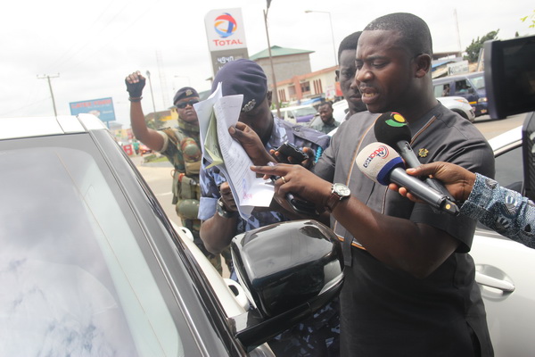 Mr Michael Sakyi (right), the Head of Special Surveillance and Monitoring Unit, GRA, scrutinising  temporary vehicle import documents from an  impounded vehicle owner during the operation. With him are some custom officers and journalists. Picture: EDNA ADU-SERWAA