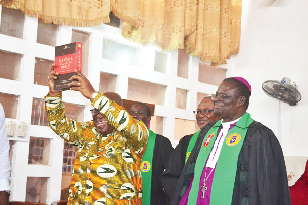 President Akufo-Addo displaying a Bible given to him by the Church with Bishop Ato Brown (right) and Very Rev Jacob William French (second right) looking on.
