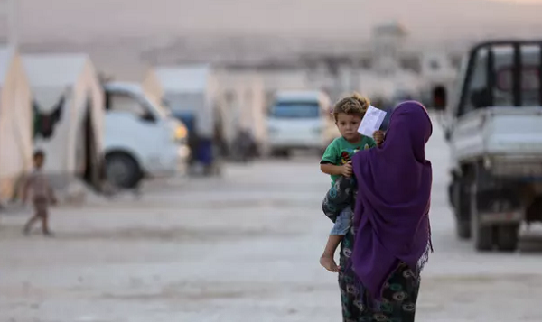 A displaced Syrian woman holds a toddler in a camp in Kafaldin. The US will reduce the number of refugees entering by a third. Photograph: Omar Haj Kadour/AFP/Getty Images