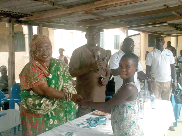   Mama Dewoname giving the NHIS card to a beneficiary of the exercise.