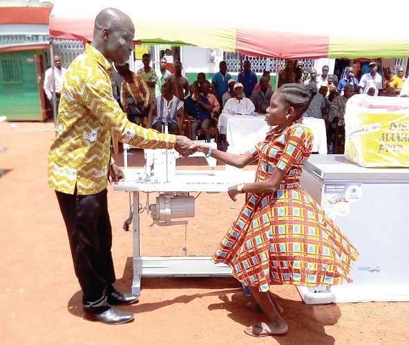 The DCE for Upper Manya Krobo District, Mr Felix Nartey Odjao, presenting an industrial sewing machine to Ms Catherine Amewu 