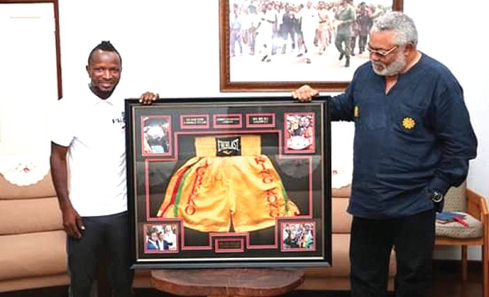 Former President Jerry Rawlings admiring the framed shorts presented to him by Joseph Agbeko (left)