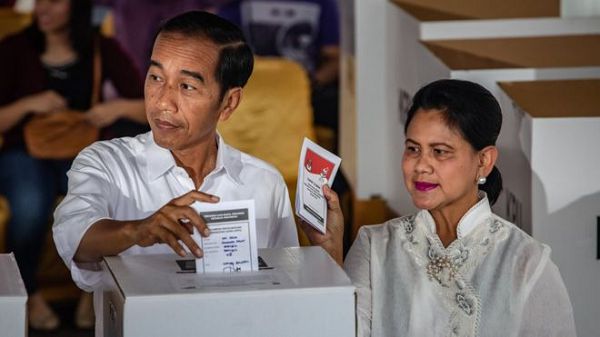 Indonesian President Joko Widodo, with his wife Iriana, votes in the election