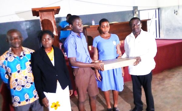 Nana Owusu Agyekum, handing over one of the machines to the head prefect of the school, Master Lord Opoku Sarkodie
