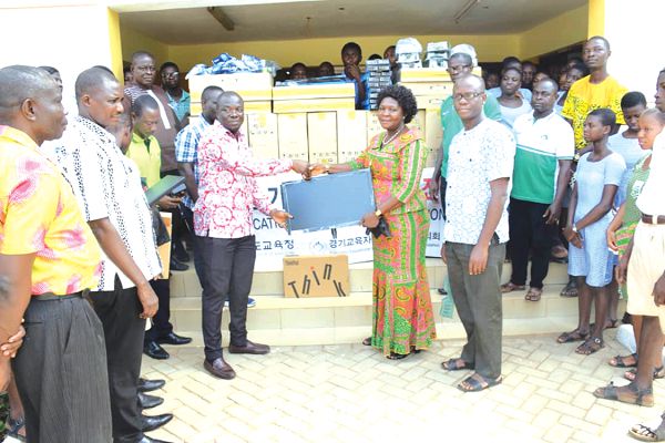 Mr Simon Kweku Tetteh (4th left) handing over one of the items he presented to MAKROSEC to Mrs Agnes Nanor, the Headmistress of the school, while staff and students look on