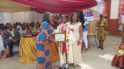 Mrs Theresa Tetteh (left) presenting the Most Hard-working and Innovative Pupil award to Miss Mildred Asamoah, a Basic Six pupil, while her mother, Mrs Gifty Asamoah, looks on