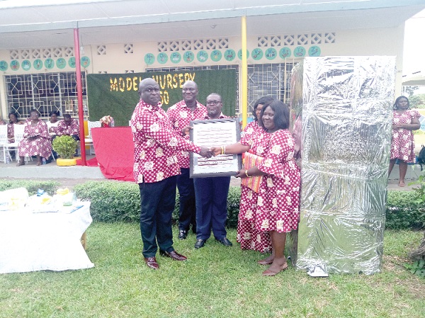 Nii Adjei Tawiah (left) being supported by some officials of the school to make a presentation to Madam Margaret Ofori