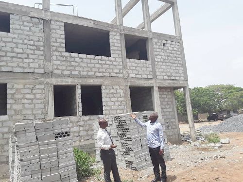 Dr Kwame Aveh, the National Chairman of the GHAPACC (with hand raised) explaining a point to Dr John Ahenkorah, a member of the association at the uncompleted building