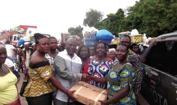 Mr Samuel Kwame Agyekum (3rd left), the DCE for Asuogyaman, presenting the raincoats to Ms Mercy Mansah Agbetorwu (right), the leader of the Atimpoku Traders Association.