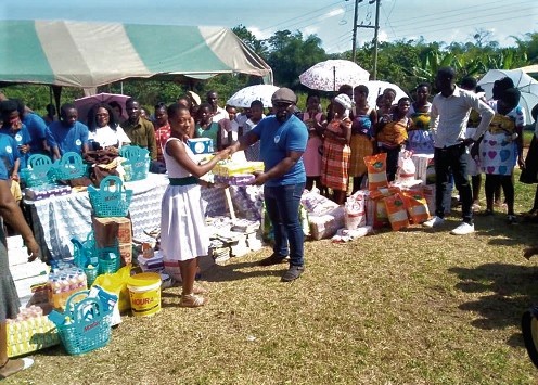 Mr Kwame Debrah, the Public Relations  Officer of Givers of Happiness, presenting some items to a beneficiary