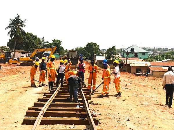 Some of the rail workers busy at work. Inset: Mr Joe Ghartey (arrowed) interacting with the workers