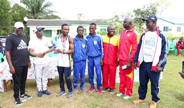 Malik Yakubu receiving the trophy from Mr Alex Agyekum, the MP of Mporhor, while other dignitaries and athletes look on