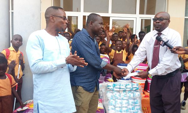 Mr Bekoe (left) presenting the cash to Mr Ametewee(in tie) With them is the Central Regional minister (extreme left) and some of the students