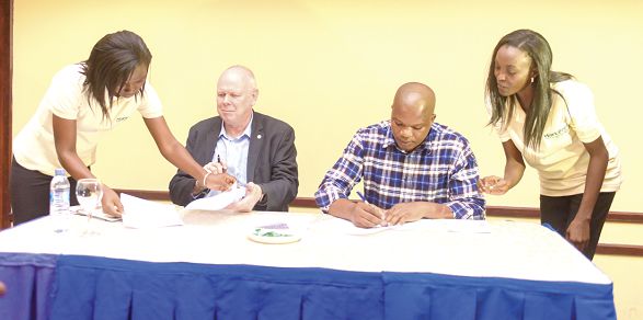 Mr Harm Duiker, Country Director of SNV (left), signing  a cooperation agreement with Mr Benjamin Agbesi, CEO of AB Farms
