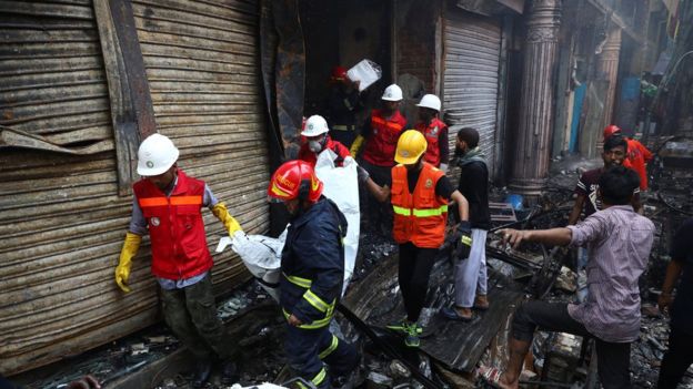 Volunteers recovering a body from a burnt warehouse