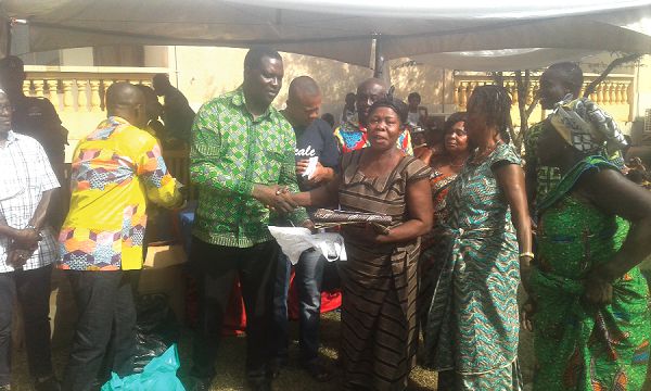  Dr Osei Yaw Adutwum presenting a piece of cloth and cash to Ms Akosua Nyarko of Fahiakobo during the event