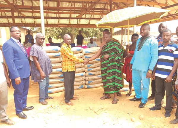 The Board Chairman, Mr Patrick Owusu (middle) presenting the 200 bags of cement to the Chief of Pakyi No2, Nana Kofi Agyei (in cloth), while the CEO of the Bank, Dr Stephen Sarfo Kantanka (extreme left in suit) and others look on