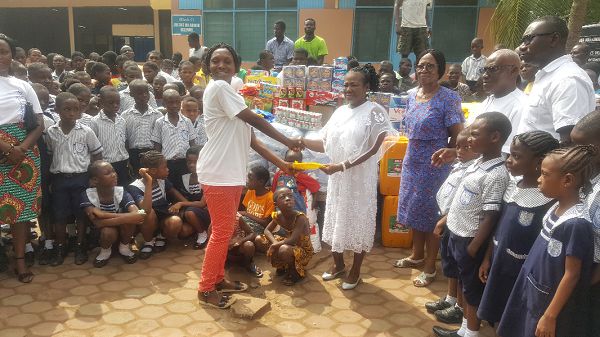 The Founder of Mercy Schools Limited, Mrs Mercy Nortey (right), presenting one of the items to the Girls Prefect of Echoing Hills Village, Miss Yaa Akoto.