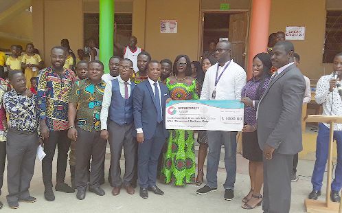 Mr Akwasi Okyere (arrowed) receiving the dummy cheque from Mr Kofi Boakye, Head of EDQ, Ghana. Looking on are staff of OISL and the Best Brain International School.